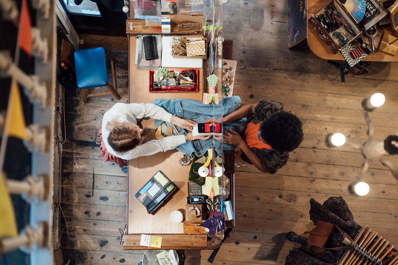 Customer paying via contactless payment with his mobile phone A young man enjoying a day out shopping in a vintage clothing store in Durham