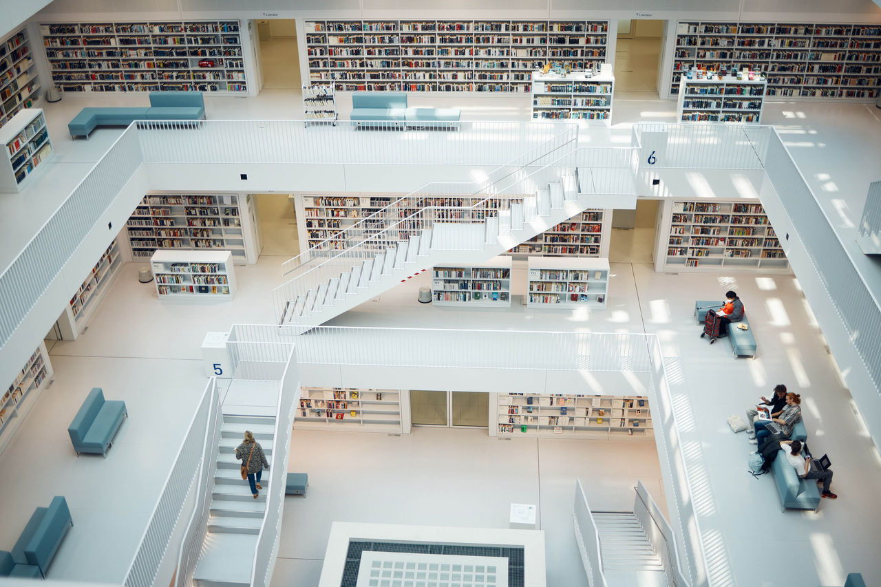 High angle shot looking down inside the Stuttgart City Library Library book shelf, choice and education people search for history books for research, university study or college. Big architecture building, knowledge learning and school students studying info.