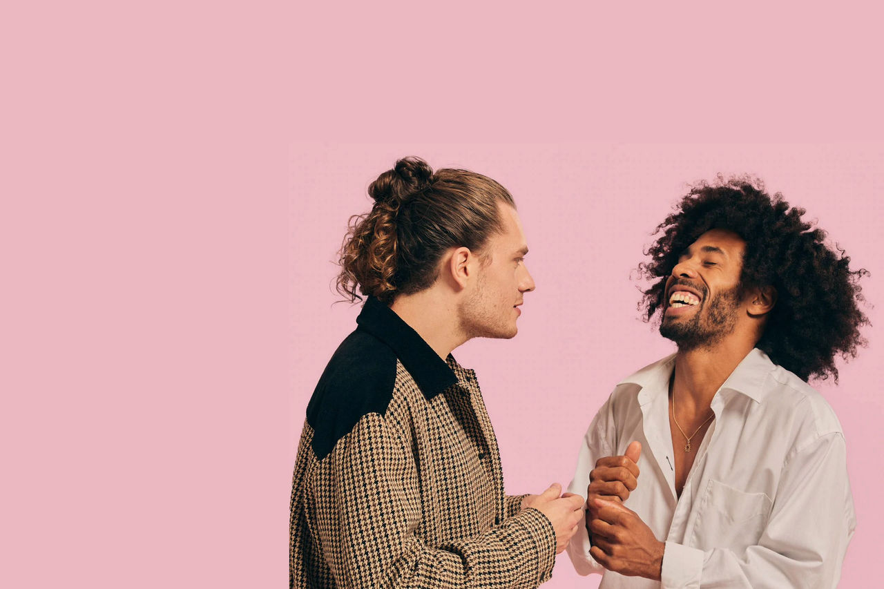 men laughing in front of a pink background