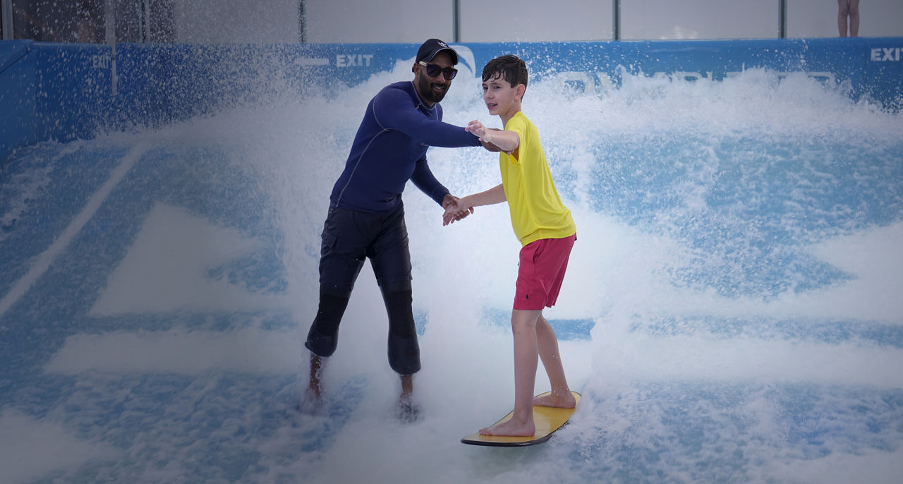 A surf instructor teaching a child how to surf
