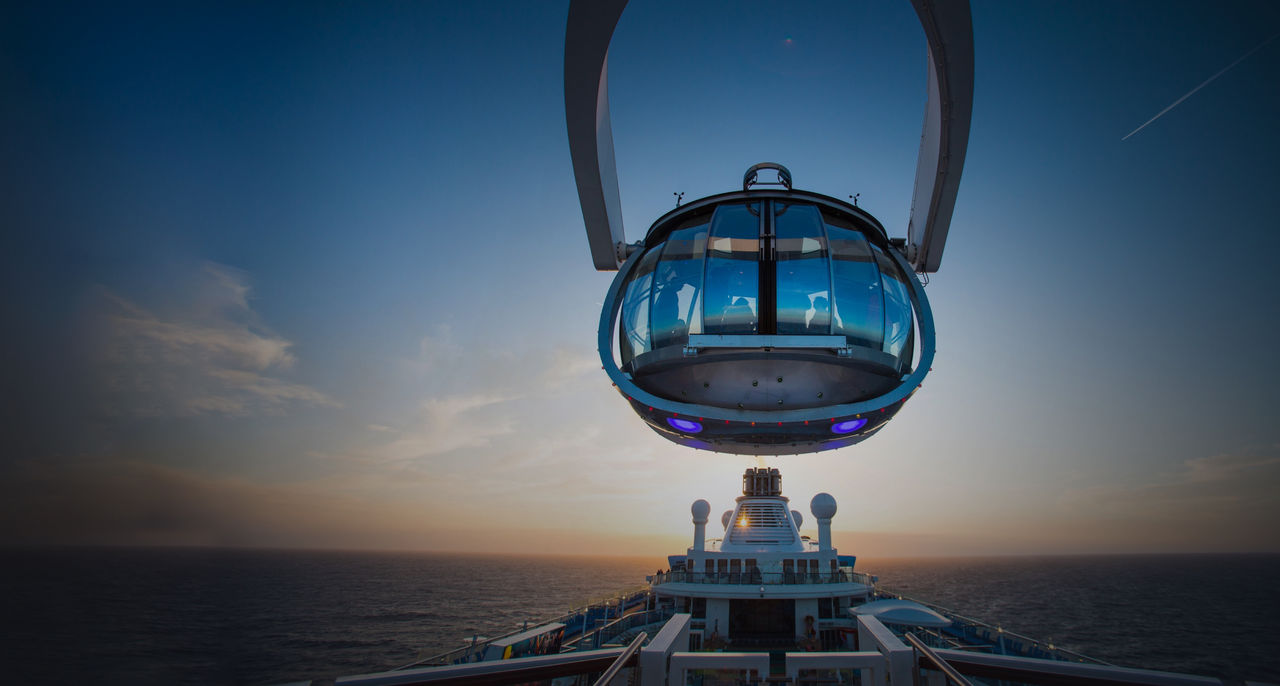 An observation pod suspended above a cruise ship at sunset